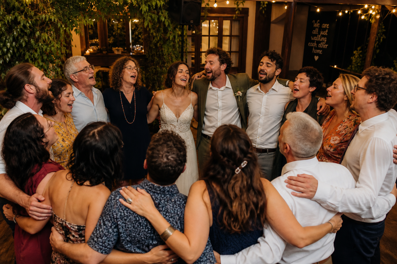 Couple and wedding guests in a circle singing together at the end of the night